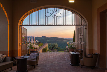 A beautiful view of the Tuscan countryside through a gated archway.
