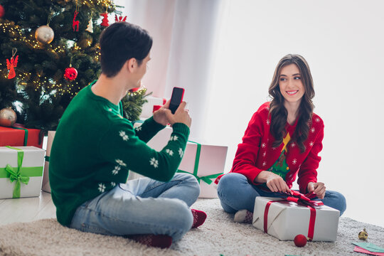 Full size portrait of two people guy hold telephone make picture photo girl unboxing xmas package festive miracle indoors