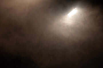 big spotlight shining in room full of smoke