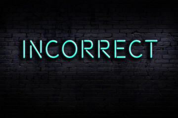 Neon sign. Word incorrect against brick wall. Night view