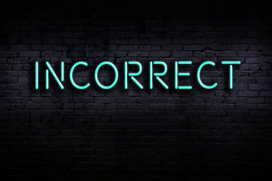 Neon sign. Word incorrect against brick wall. Night view