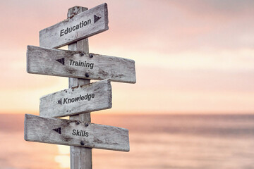 education training knowledge skills text written on wooden signpost outdoors at the beach during...
