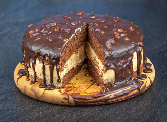 Sliced chocolate sponge cake with almonds on a round cutting board.