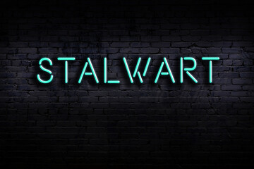 Neon sign. Word stalwart against brick wall. Night view