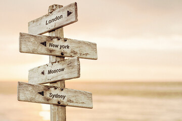 london new york moscow sydney text written on wooden signpost outdoors at the beach during sunset
