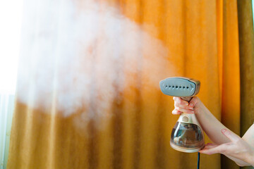 Working portable hand steamer for clothes in women's hands. 