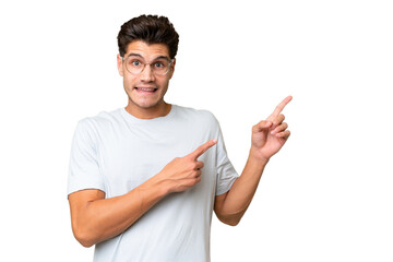 Young caucasian handsome man over isolated background frightened and pointing to the side