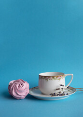 Homemade pink zephyr or marshmallow with white porcelain cup and lavander close to. Isolated on blue background. Sweet Meringue dessert. Valentineâ€™s or Mothers Day concept.