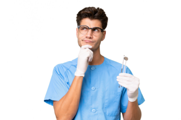 Young dentist man holding tools over isolated background having doubts and thinking