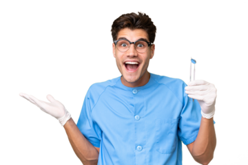 Young dentist man holding tools over isolated background with shocked facial expression