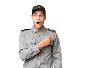 Young security man over isolated background surprised and pointing side