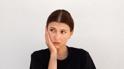 Portrait of pensive young woman looking away on white background. Caucasian woman wearing black T-shirt posing with doubtful expression. Uncertainty and doubt