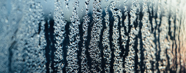 Fototapeta na wymiar Texture of misted glass in winter. Frozen drops of water in sun on window.