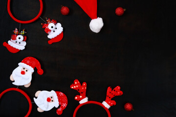 Christmas accessories on a dark wooden table background, top view. New Year and Christmas concept. Headbands, Christmas balls and a red cap