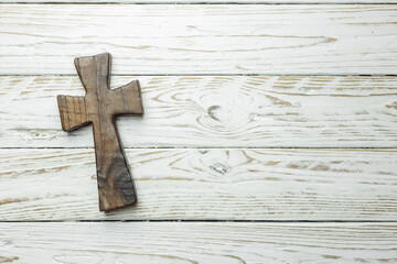 dark wooden cross on white wooden board in horizontal position. space copy. space for text. religious background.