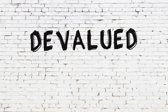 Inscription devalued painted on white brick wall