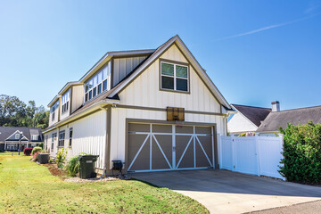 The rear back side of a long cottage style new construction cream white house with tan trim and a...