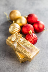 Two gold christmas gifts and christmas balls on gray table.