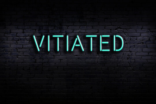 Neon sign. Word vitiated against brick wall. Night view