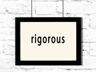 Black frame hanging on white brick wall with inscription rigorous