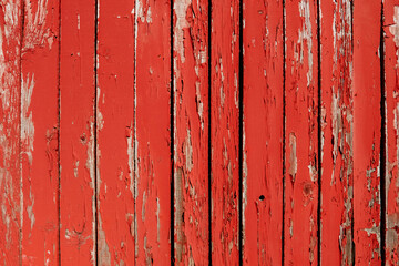 Background of old wooden boards painted with red cracked paint. Old fence or building wall made of...