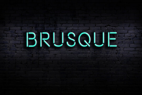 Neon sign. Word brusque against brick wall. Night view