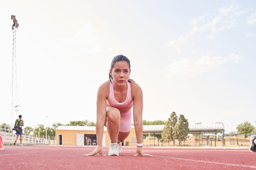 young woman training. latin female athlete running on an athletics track.