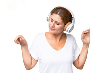 Middle-aged caucasian woman over isolated background listening music and dancing