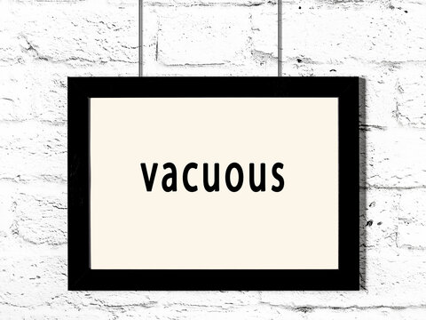 Black frame hanging on white brick wall with inscription vacuous