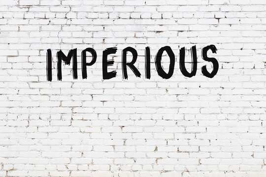 Inscription imperious painted on white brick wall