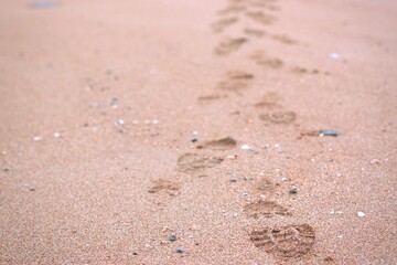 Footprints on the sand, the imprint of the shoes of a man tangling along the seashore, selective focus, blurred background, the coast of the Sea of Azov, Russia