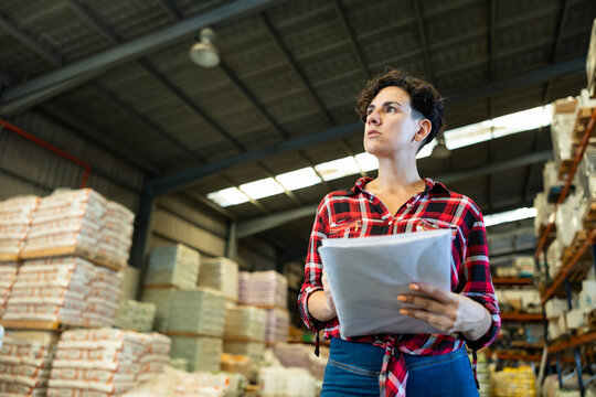 Female storekeeper checks the availability of goods with documents in the building materials warehouse