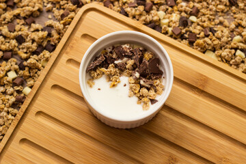 Granola in a bowl surrounded by granola on table. Granola background