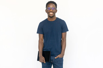 Fototapeta premium Smiling man standing with tablet. Young African American male model holding tablet and smiling with in hand in pocket. Portrait, studio shot, technology concept