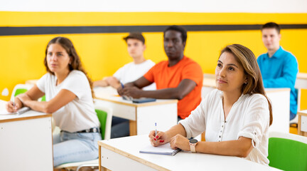 Obraz premium Portrait of focused adult female studying in classroom with colleagues