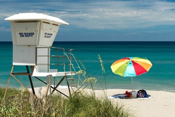 Lifeguard tower with a colorful umbrella on a sandy beach in West Palm Beach, Florida, USA