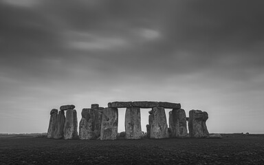 A moody black and white image of the iconic prehistoric neolithic standing stone circle Stonehenge, a pagan site of ritual dating back to the Bronze Age, at Salisbury Plain, Wiltshire, England, UK.