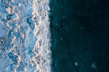 Top view of the icy seashore. Winter aerial photograph of the sea coast. Ice floes and freezing sea...
