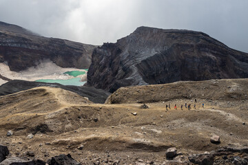 Majestic mountain landscape. A group of hikers is walking near the crater of the volcano. Lake in a...