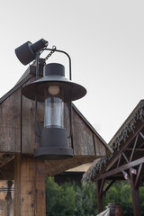 Black vintage railroad station lantern hung from a wooden post.