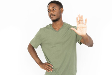 Dissatisfied young man showing stop sign. Male African American model in green T-shirt showing his...