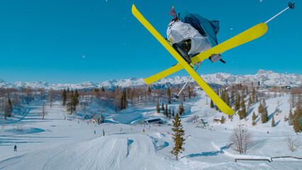 CLOSE UP: Stunning view of freestyle skier doing grab trick while jumping kicker