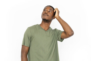 Thoughtful young man looking up. Male African American model in green T-shirt holding his hand on head and thinking about something. Thoughts, dreaming concept