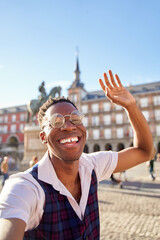 Young African-American man sightseeing in the streets of Madrid. He takes a selfie for social media.