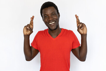 Portrait of happy African American man crossing fingers. Excited young male model with short dark...
