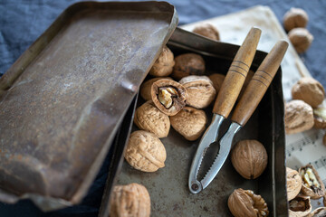 Nutcracker with walnuts in a rusty tin box on music paper on a white table. Place for your text
