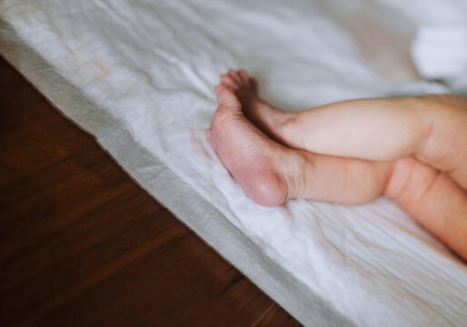 Small legs, feet of a newborn baby sleeping on the bed of a small child close-up.
