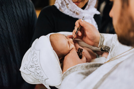 The priest in the church conducts a sacred rite, the ritual of anointing the head of a newborn child. photography, religion.
