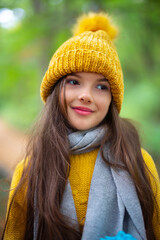 Portrait of beautiful girl or young woman outdoor in autumn forest. Lady with winter hat and scarf.