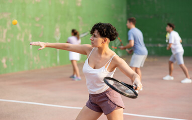 Fototapeta na wymiar Focused woman playing frontenis with partners at sunny day, healthy lifestyle concept